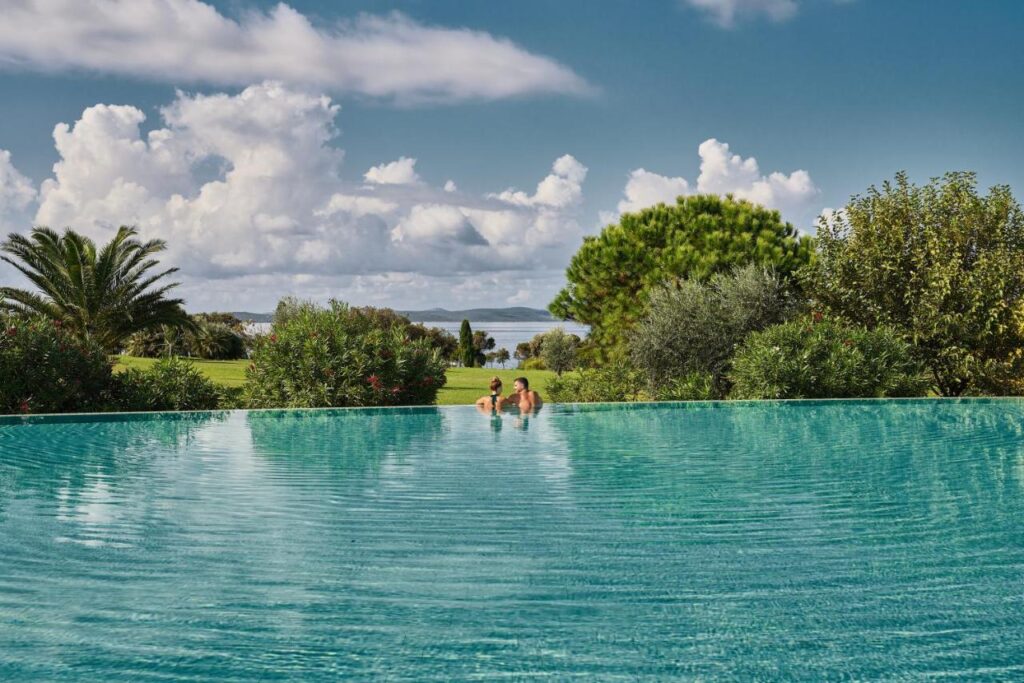Image shows a couple in a outdoor pool with amazing sea view in Falkensteiner hotel