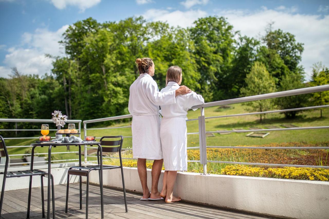 Image shows a couple overlooking the scenic nature view from the balcony of Hotel Terme Sveti Martin