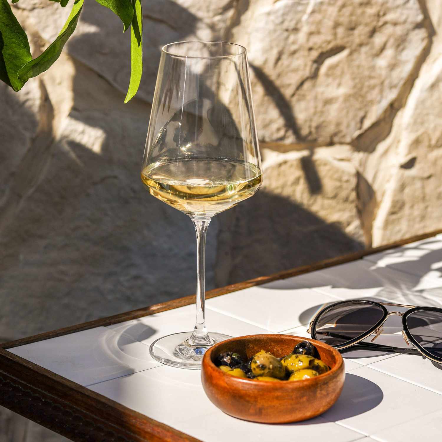 Image of Malvazija wine in a glass with olives on a table