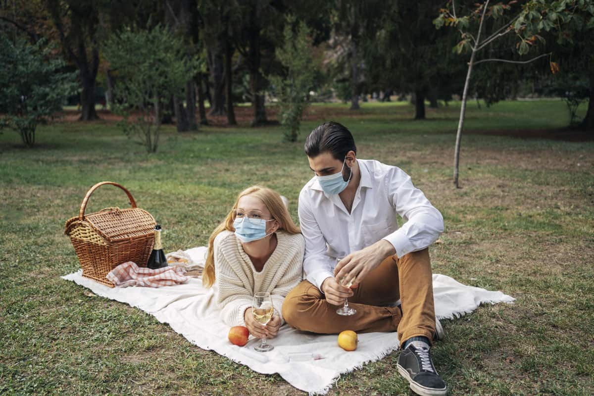 Couple having picnic while wearing medical masks