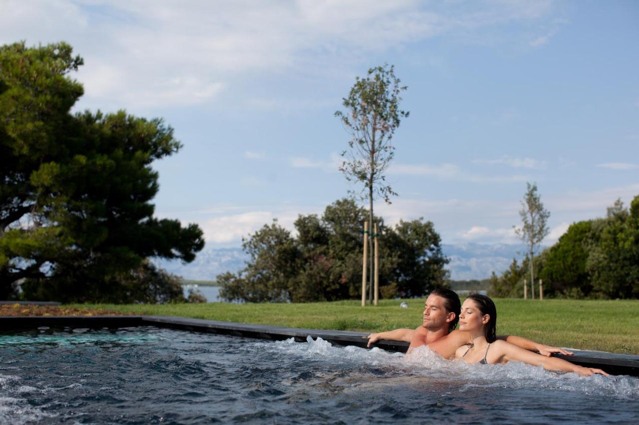 Image shows a couple in an outdoor pool of a Falkensteiner hotel