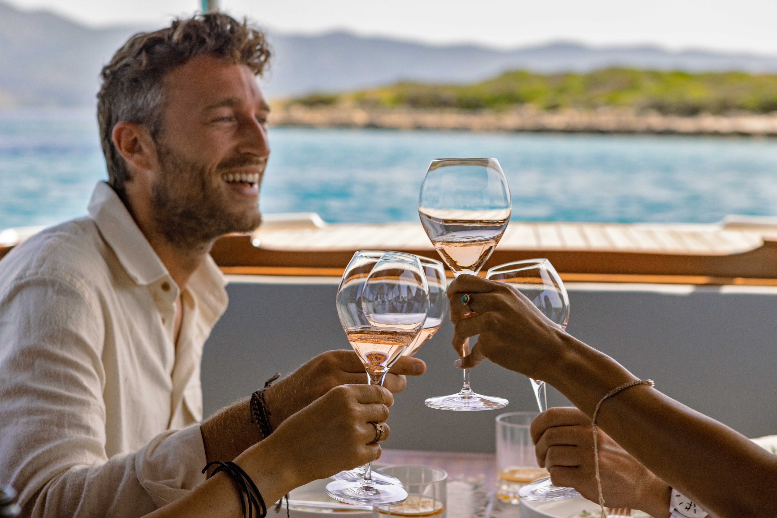 Image of frineds enjoying wine in a restaurant with panoramic sea view