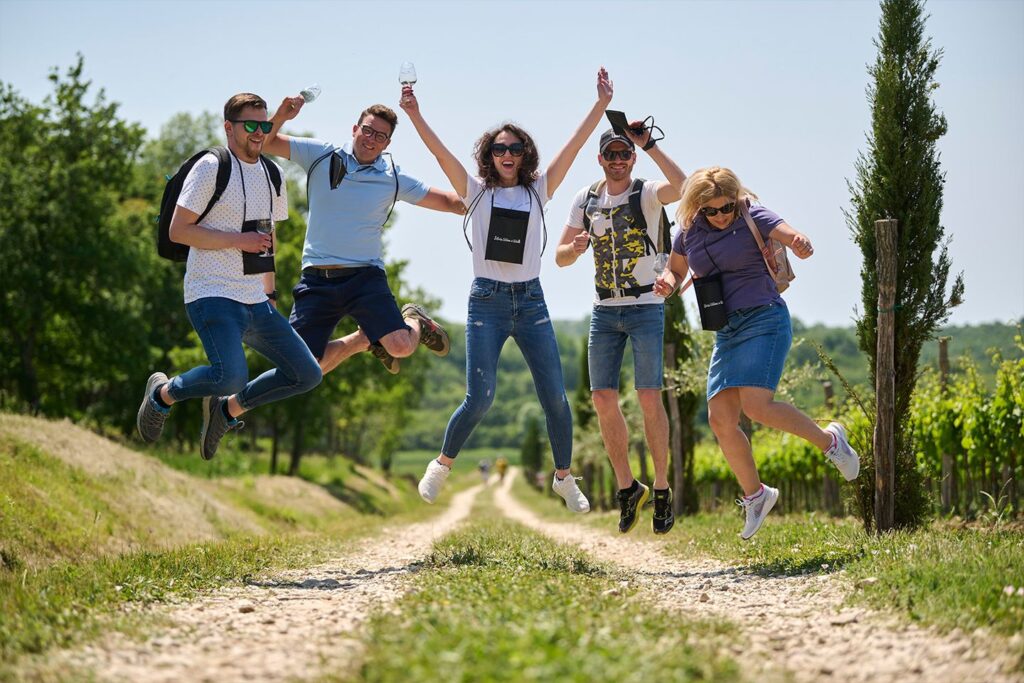 Image of Istria wine and walk visitors happily jumping in the vineyards