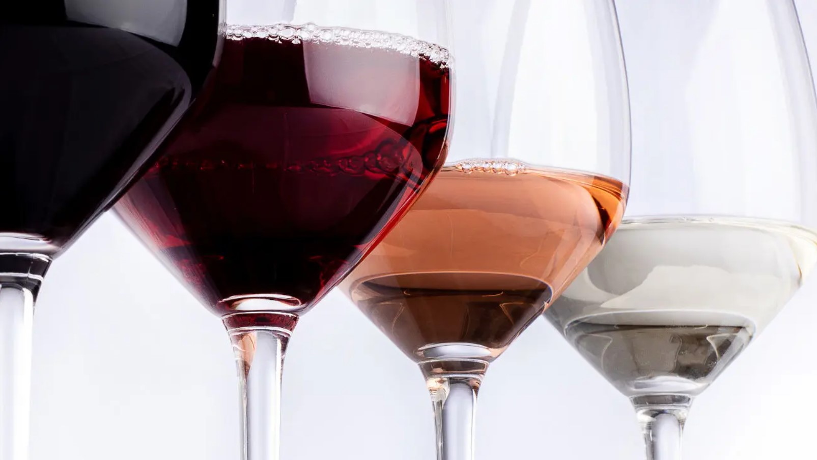 Image of four glasses of clear wine, from red to rose to white wine