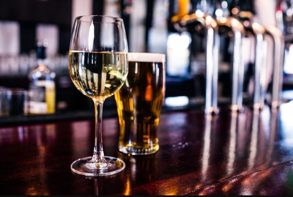Image of a wine glass and a glass of beer on a bar