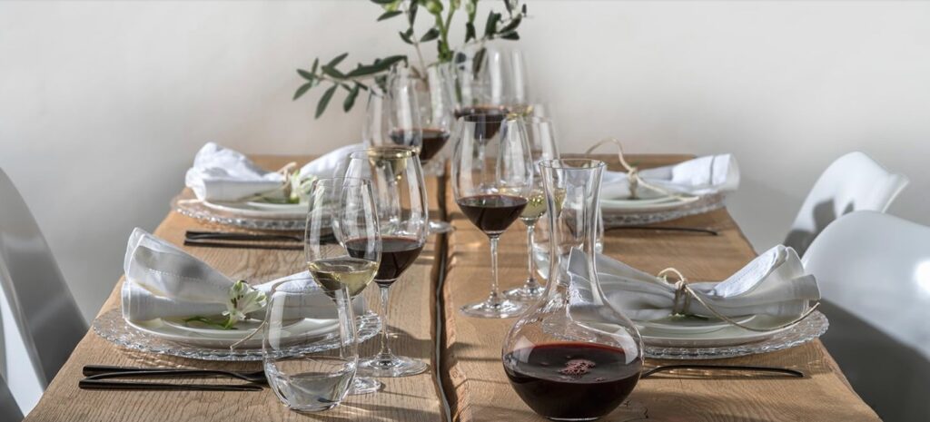 Image of a table set for dinner with two sets of Riedel wine glasses