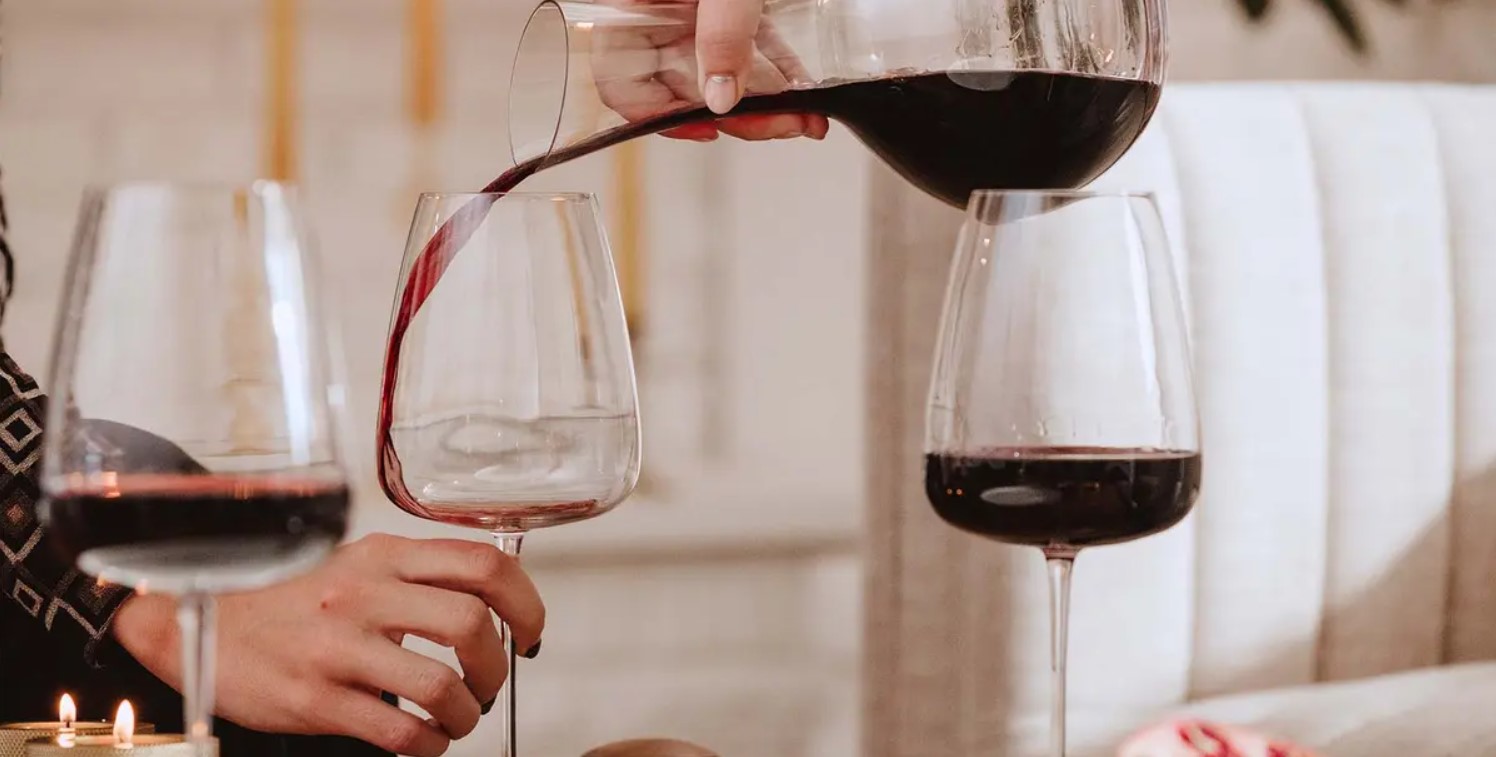 Image of a red wine being poured in red wine glasses from decanter